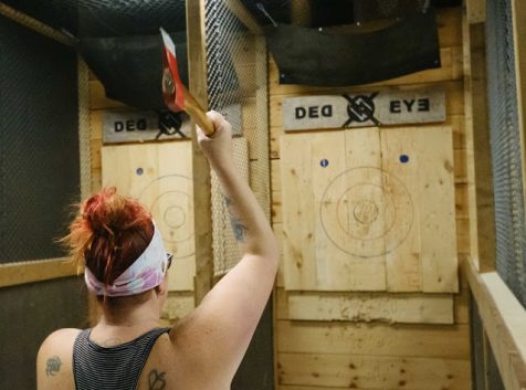 A photo of a person throwing an axe at a target on the wall in front of them.