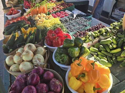 A photo of a farmers' market stand with baskets of colourful vegetables and berries.