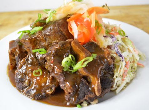 Photo of a plate of food that looks like meat with brown sauce and cole slaw on the side.