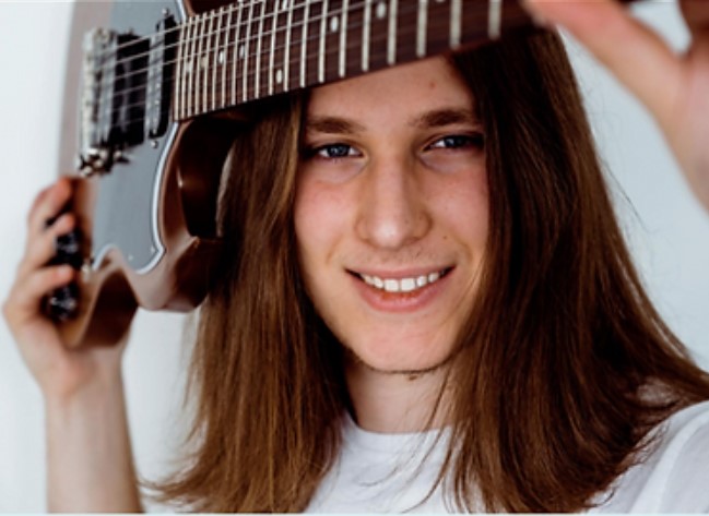 Photo of Mason (the performer) holding a guitar.