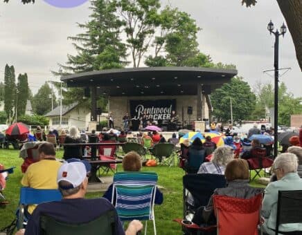 Image of an outdoor stage with a crowd of people in lawn chairs.
