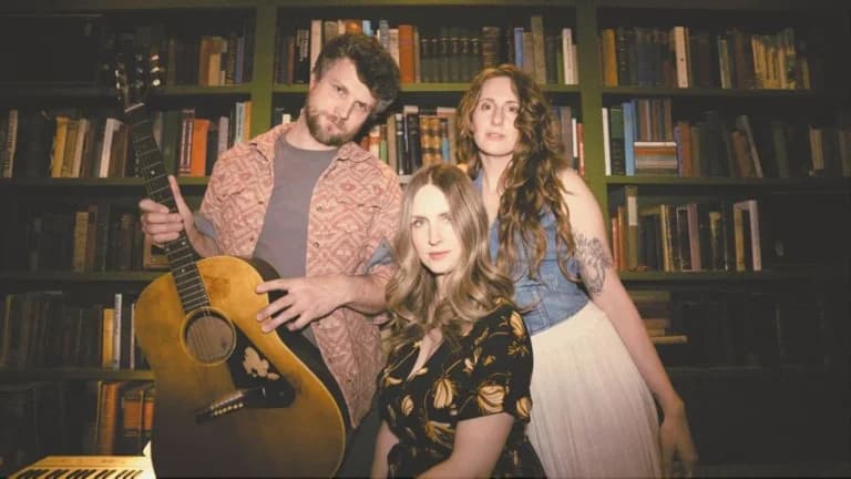guy with guitar and two women posing