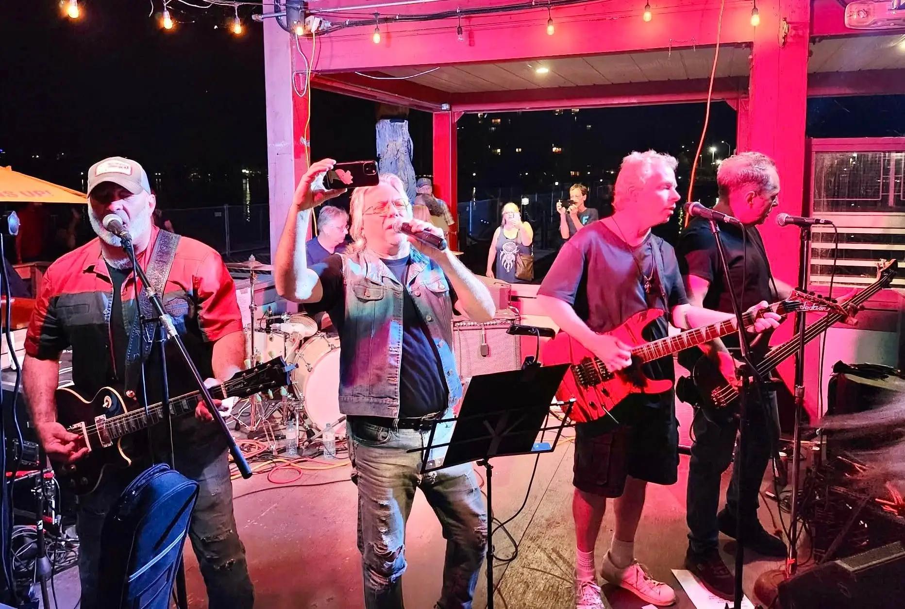Band of men singing and playing instruments on stage